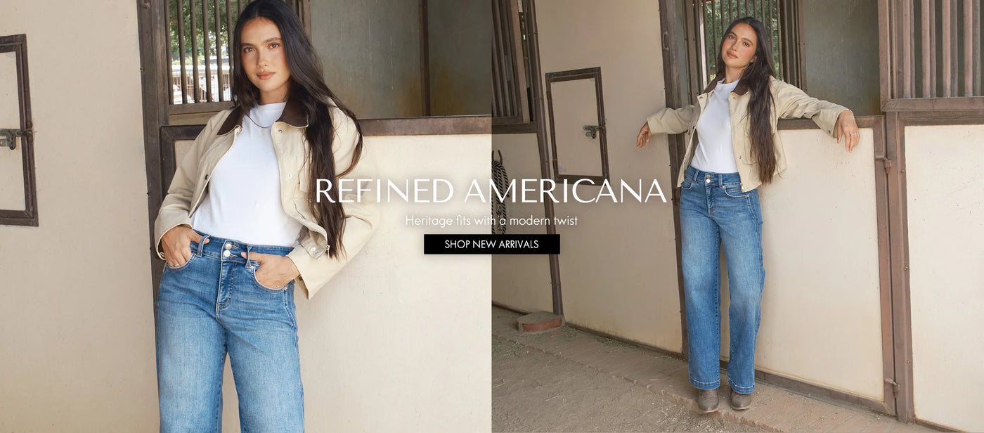Woman wearing a beige jacket and blue jeans standing in front of a wooden door.
