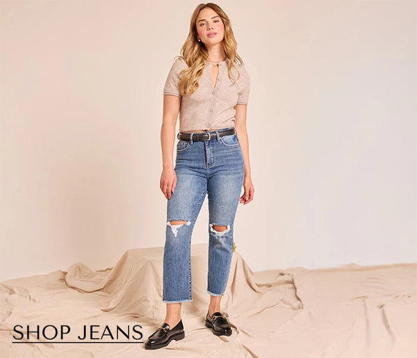 Woman wearing ripped jeans with a plain background and 'Shop Jeans' text.